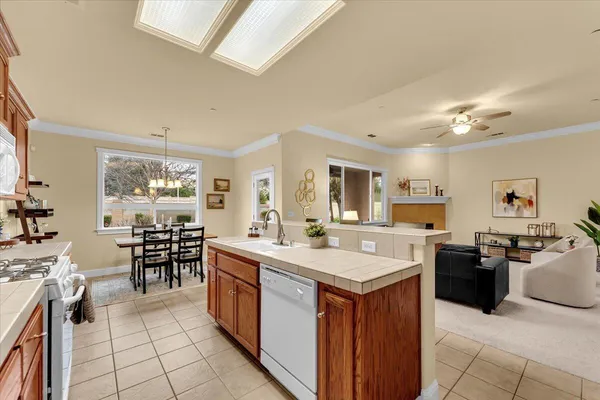 a large kitchen with kitchen island a sink a stove a dining table and chairs with wooden floor