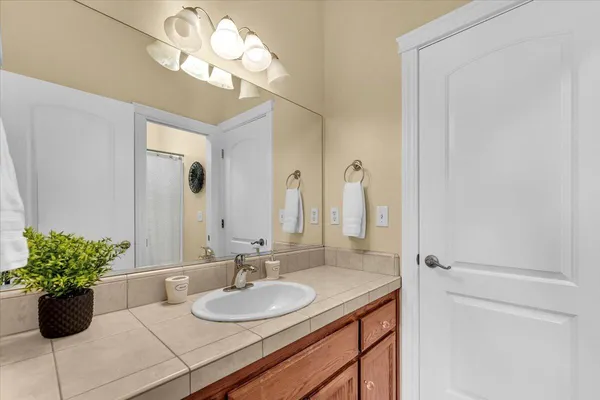 a bathroom with a granite countertop sink a large mirror and a shower