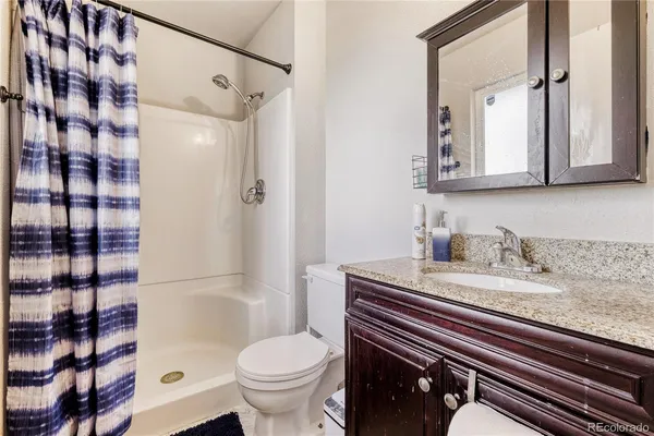 a bathroom with a granite countertop sink toilet mirror and shower