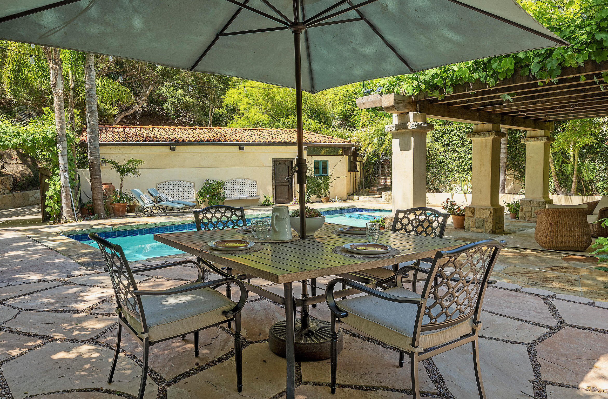 1493 Sycamore Canyon Road Montecito, CA 93108 - Photo 37 of 47 a patio with a yard table and chairs under an umbrella