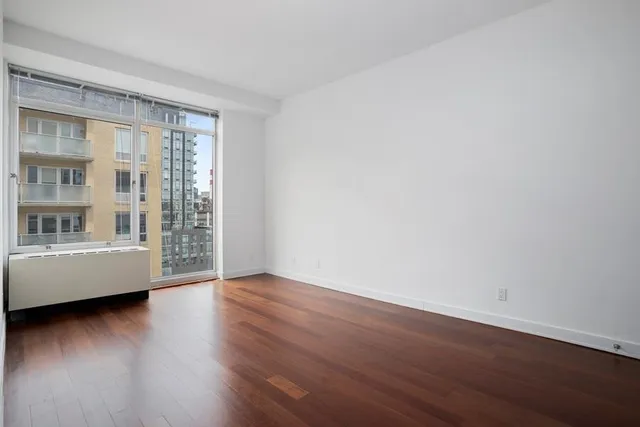 a view of a hallway with wooden floor and a bathroom