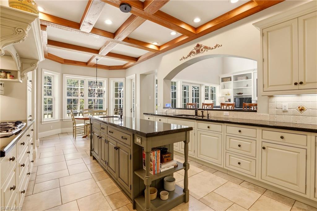 4335 7th Avenue Southwest Naples, FL 34119 - Photo 11 of 49 Kitchen featuring open shelves, decorative backsplash, coffered ceiling, dark stone counters, and light tile patterned floors