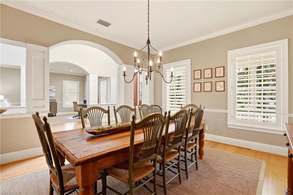4335 7th Avenue Southwest Naples, FL 34119 - Photo 15 of 49 Dining room featuring arched walkways, suspended lighting, light wood-style flooring, and ornamental molding
