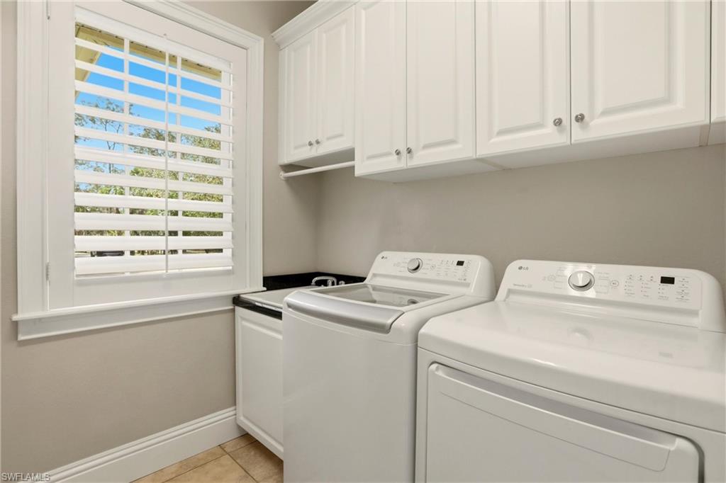 4335 7th Avenue Southwest Naples, FL 34119 - Photo 36 of 49 Laundry area featuring washer and dryer, light tile patterned flooring, and cabinet space