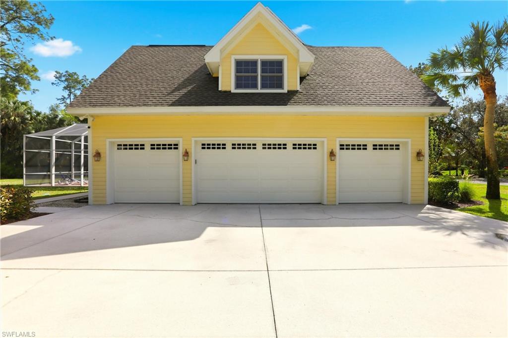 4335 7th Avenue Southwest Naples, FL 34119 - Photo 41 of 49 View of home's exterior featuring a shingled roof, a garage, concrete driveway, a sunroom, and glass enclosure