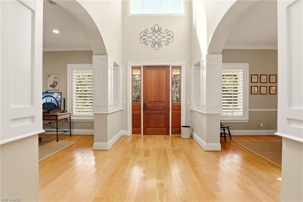 4335 7th Avenue Southwest Naples, FL 34119 - Photo 5 of 49 Foyer with ornamental molding, a high ceiling, light wood finished floors, and arched walkways