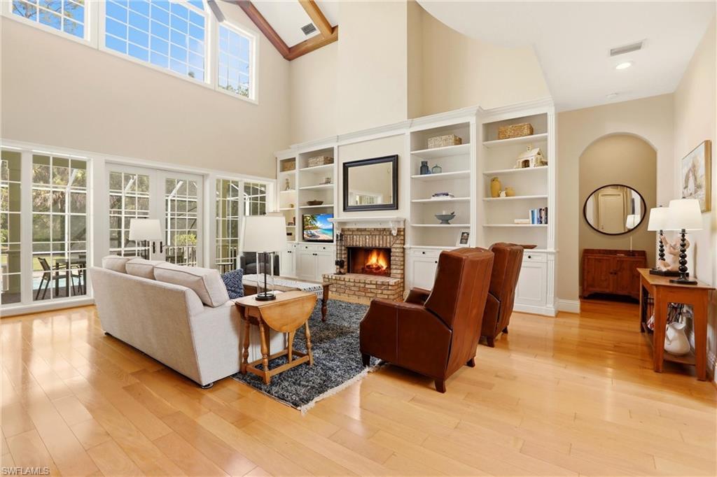 4335 7th Avenue Southwest Naples, FL 34119 - Photo 6 of 49 Living room featuring a brick fireplace, light wood-type flooring, and a high ceiling