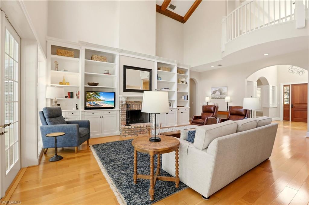 4335 7th Avenue Southwest Naples, FL 34119 - Photo 7 of 49 Living room with arched walkways, a fireplace, light wood-style flooring, and built in shelves