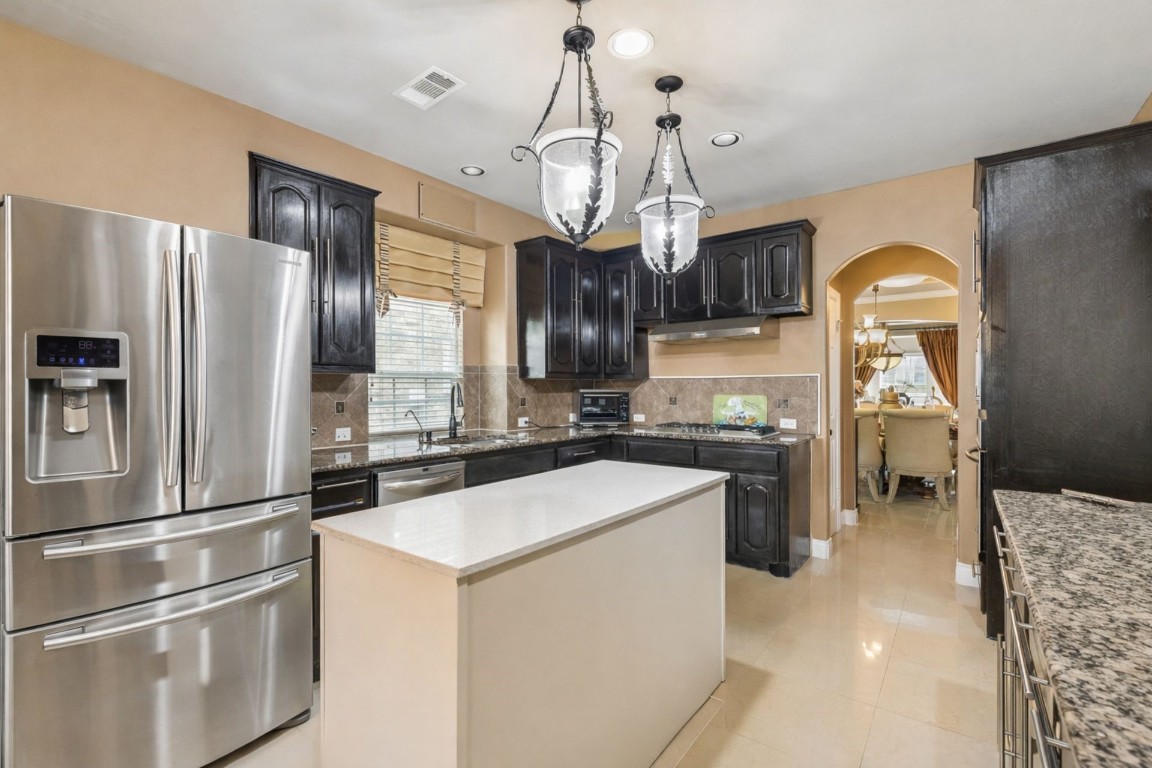 8211 Paddle Rock Lane Rosenberg, TX 77469 - Photo 7 of 24 a kitchen with stainless steel appliances a stove a refrigerator and a chandelier
