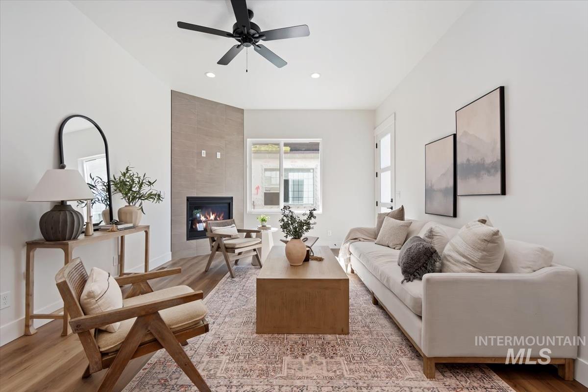 Living room featuring a fireplace, light wood-type flooring, ceiling fan, and recessed lighting