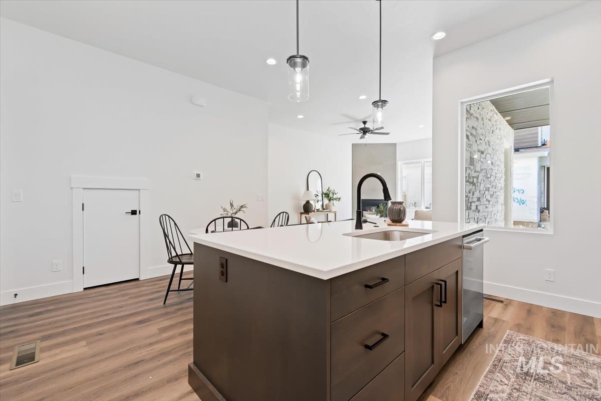 720 South Calhoun Place Star, ID 83669 - Photo 16 of 43 Kitchen featuring dark brown cabinetry, decorative light fixtures, light wood-style floors, a kitchen island with sink, and recessed lighting