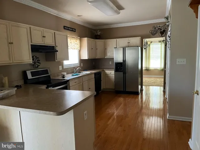 a kitchen with stainless steel appliances granite countertop a refrigerator a sink a stove and white cabinets