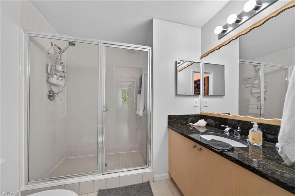 1105 Reserve Court, Unit 206 Naples, FL 34105 - Photo 16 of 23 a bathroom with a granite countertop sink a mirror a shower and vanity