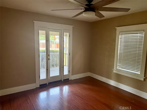 a view of an empty room with wooden floor and a window
