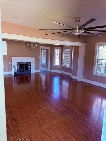 a view of an empty room with a window and wooden floor