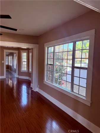 a view of an empty room with a window and wooden floor