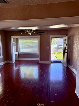a view of empty room with wooden floor and kitchen view