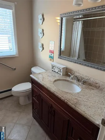 a bathroom with a granite countertop sink a mirror and a toilet