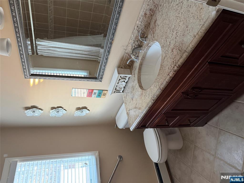 37 Park Row, Unit 2 Wallington, NJ 07057 - Photo 17 of 33 a bathroom with a granite countertop sink a mirror and a toilet