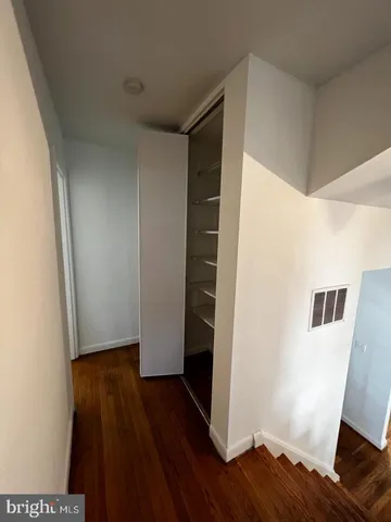 a view of an empty room with wooden floor and a ceiling fan