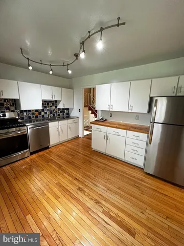 a large kitchen with stainless steel appliances granite countertop a refrigerator and a stove top oven
