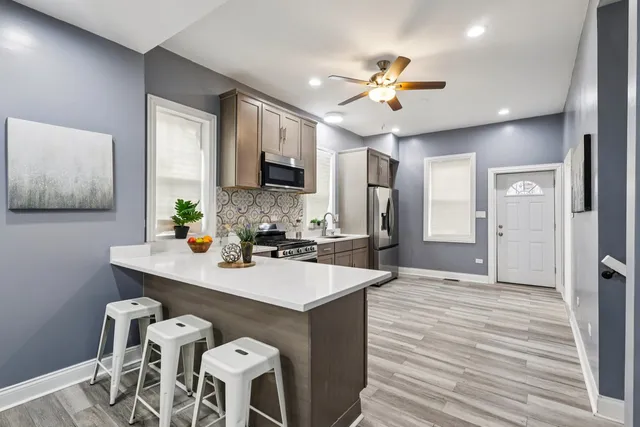 a kitchen with stainless steel appliances granite countertop a refrigerator a sink dishwasher a stove and white cabinets with wooden floor