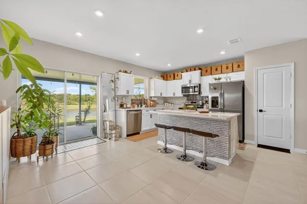 a kitchen with granite countertop a refrigerator a stove a sink a dining table and chairs