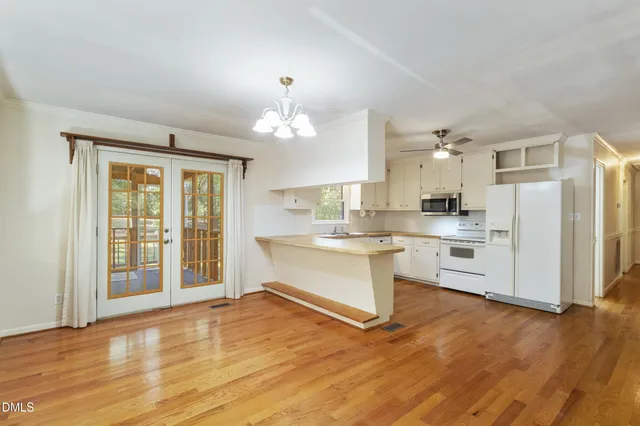 a large white kitchen with granite countertop a stove top oven a sink and white cabinets with wooden floor