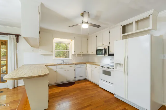a kitchen with granite countertop white cabinets white stainless steel appliances a sink and a window