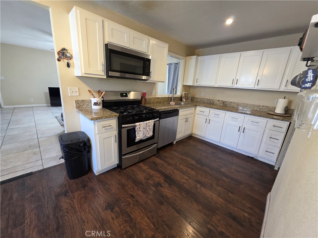 338 South Gilbert Street Hemet, CA 92543 - Photo 4 of 14 a kitchen with granite countertop a stove a sink and a microwave