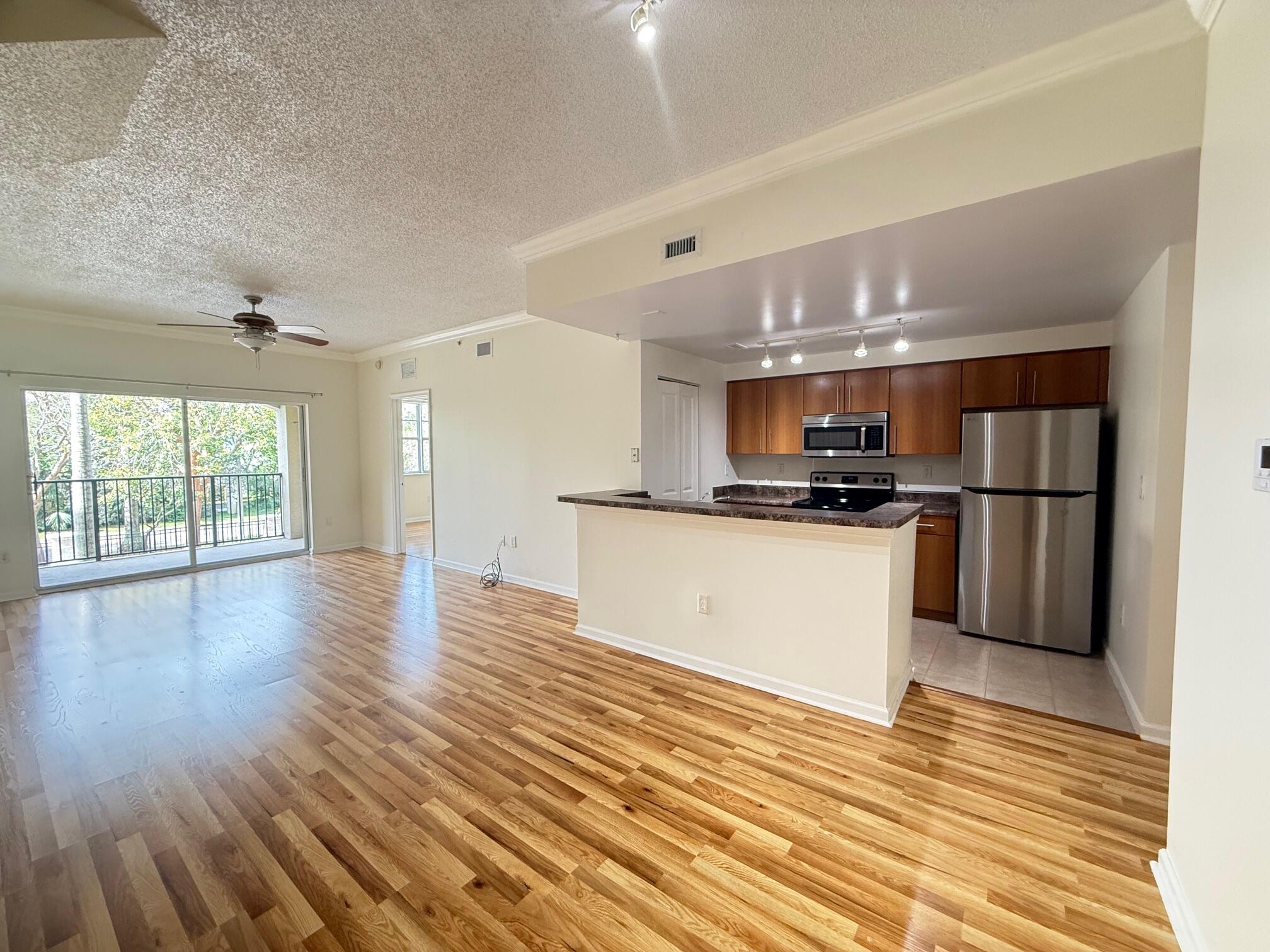 5800 West Sample Road, Unit 207 Coral Springs, FL 33067 - Photo 2 of 22 a view of kitchen with refrigerator and wooden floor