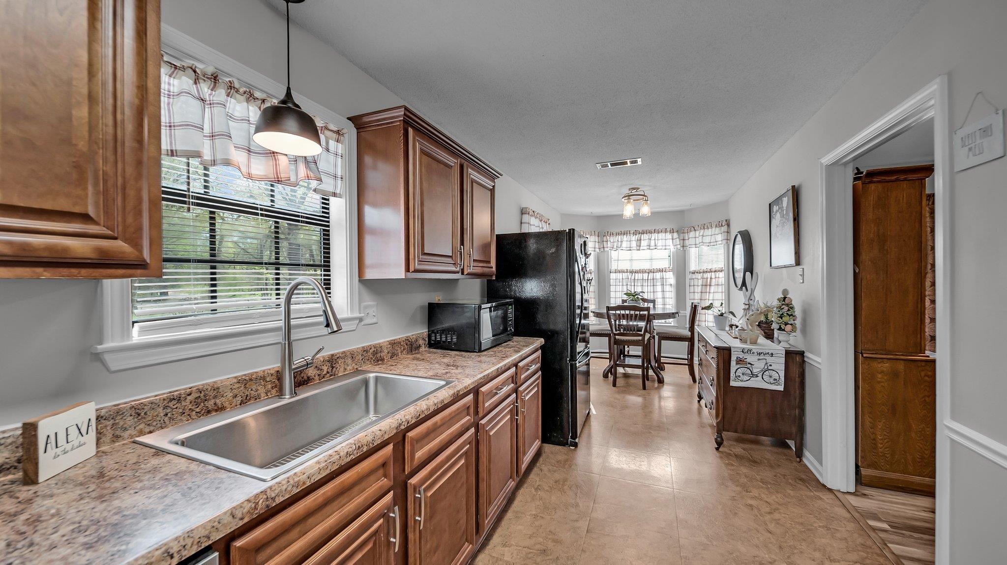 6488 Chase Road Millington, TN 38053 - Photo 12 of 22 Kitchen featuring decorative light fixtures, a sink, visible vents, black appliances, and brown cabinetry