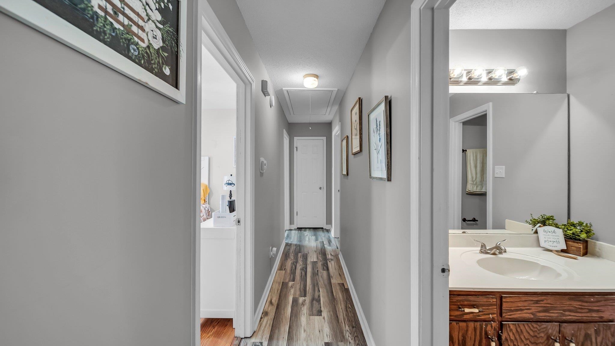 6488 Chase Road Millington, TN 38053 - Photo 13 of 22 Hallway with a textured ceiling, baseboards, wood finished floors, attic access, and a sink
