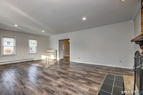 a view of an empty room with wooden floor and a window