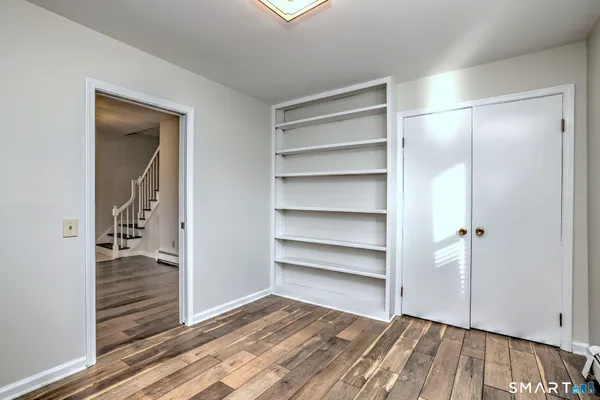 a view of an empty room with wooden floor and closet