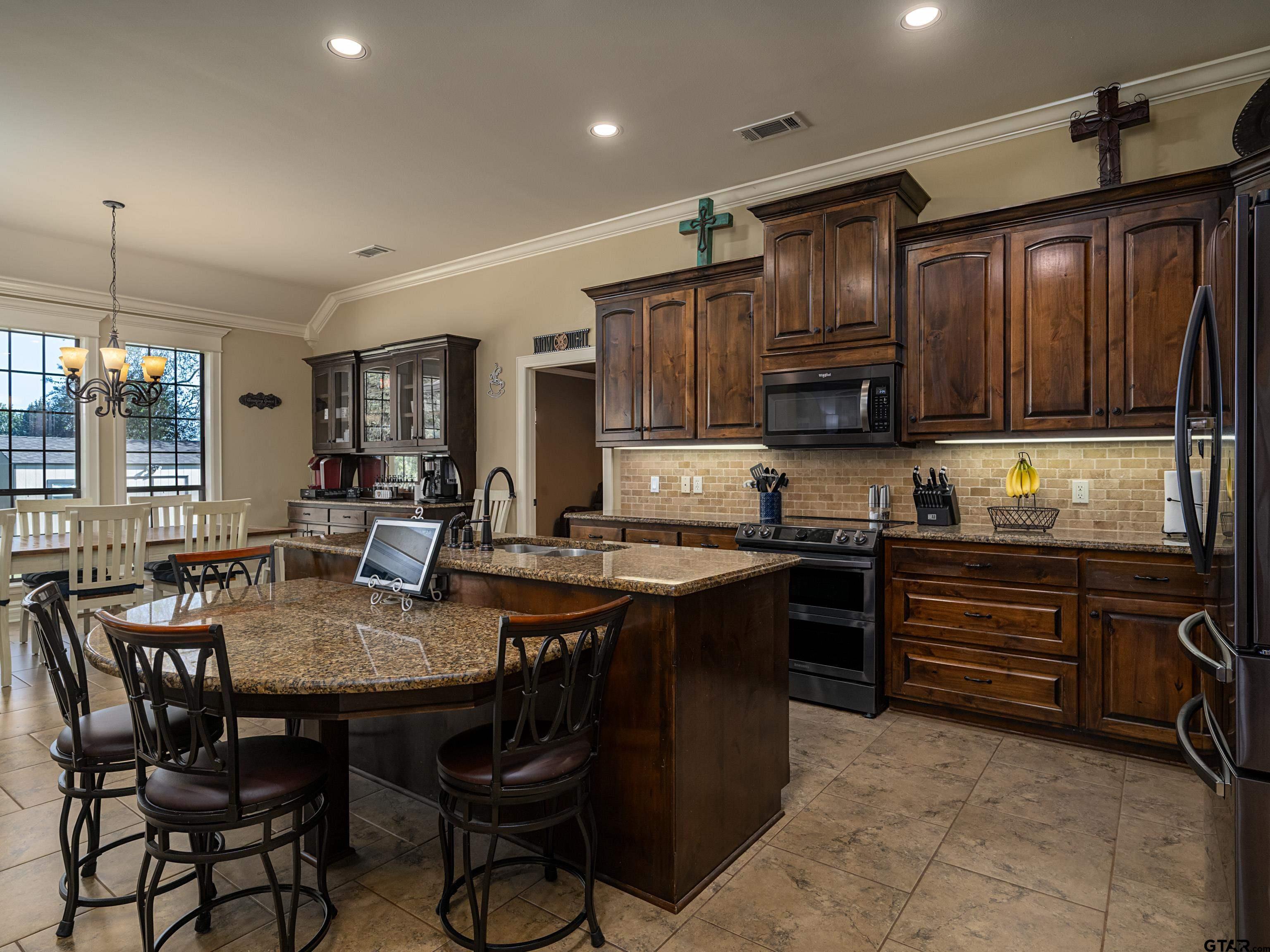19560 Sandhill Lane Flint, TX 75762 - Photo 13 of 35 a kitchen with granite countertop a table chairs stove and cabinets