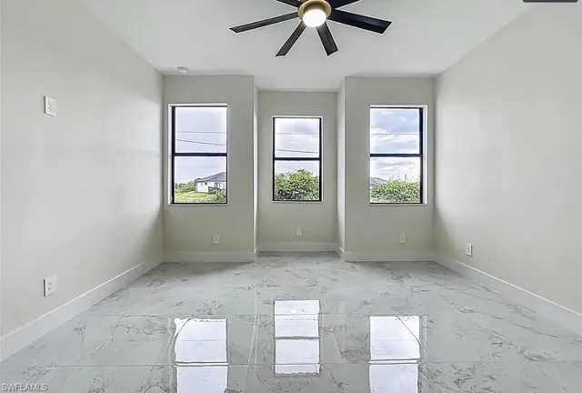 an empty room with windows and ceiling fan