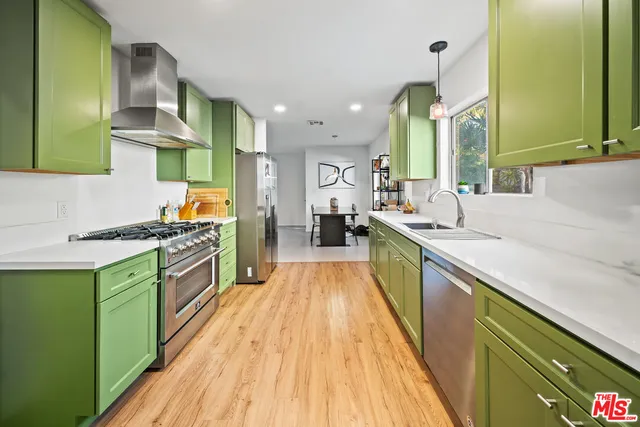 a large kitchen with stainless steel appliances granite countertop a lot of counter top space and wooden floor