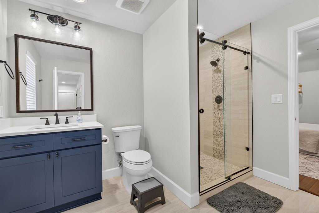 608 South Dooley Street Grapevine, TX 76051 - Photo 24 of 38 a bathroom with a toilet a sink a glass door a shower a mirror and vanity