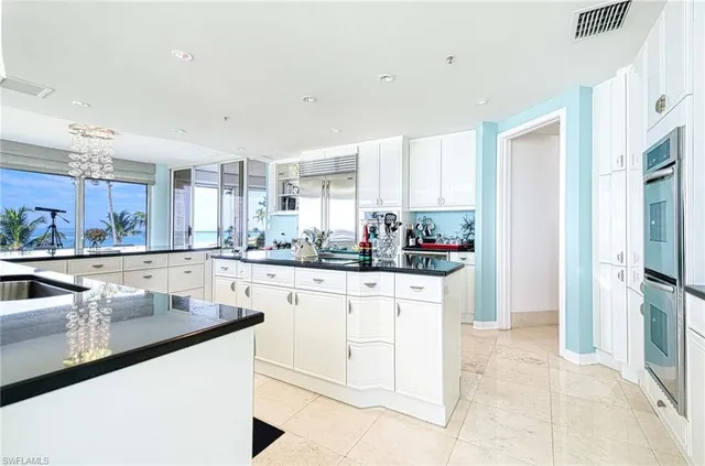 a kitchen with stainless steel appliances granite countertop a refrigerator a sink dishwasher and white cabinets next to a window