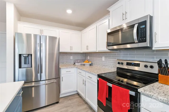 a kitchen with stainless steel appliances white cabinets and a stove top oven
