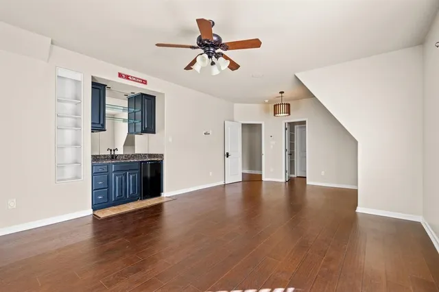 a view of an empty room with a kitchen and wooden floor