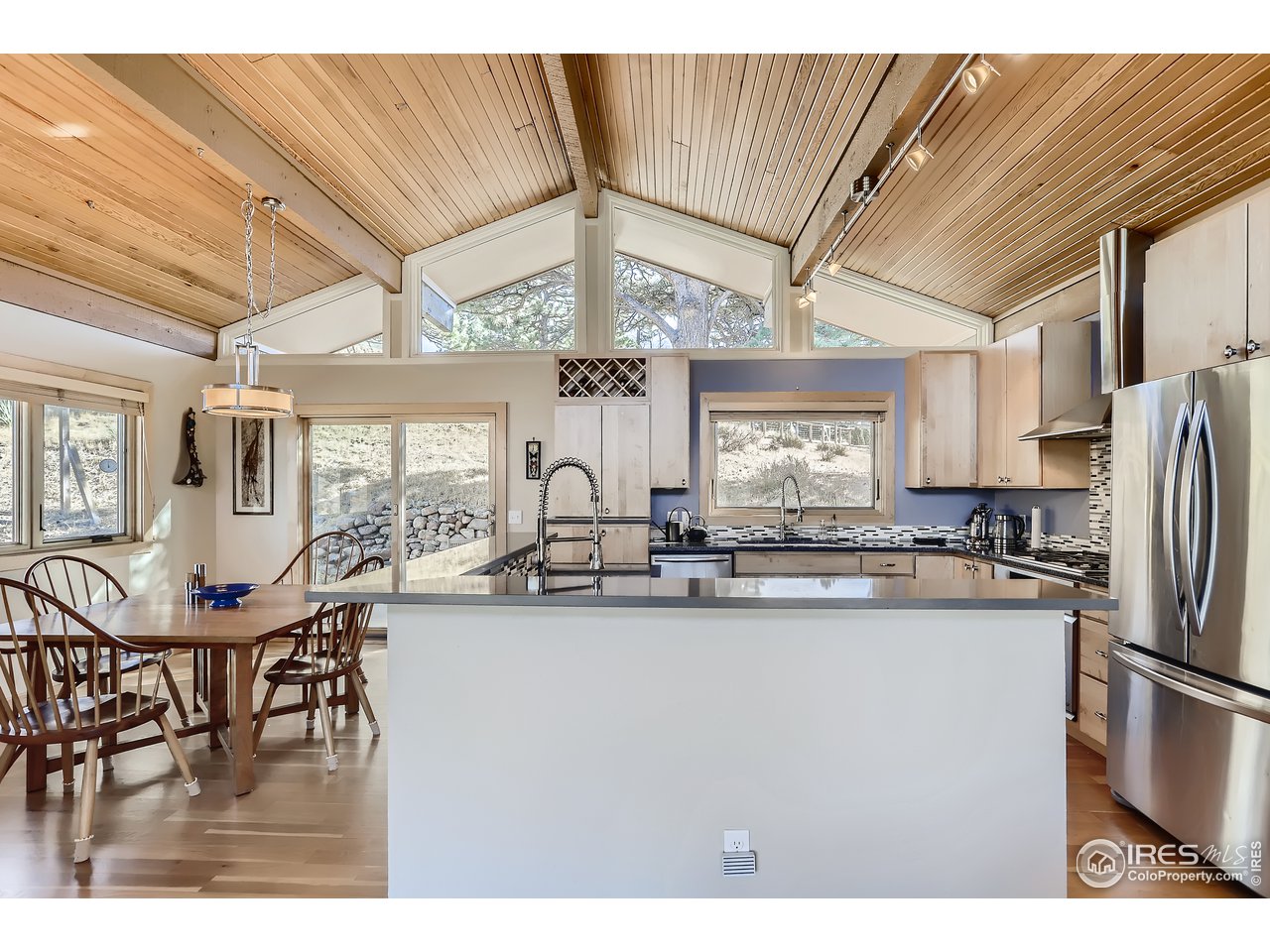 389 South Cedar Brook Road Boulder, CO 80304 - Photo 7 of 30 a kitchen with stainless steel appliances granite countertop a sink a kitchen island a stove a dining table and chairs with wooden floor