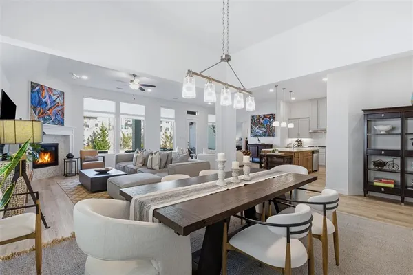 a view of a dining room and livingroom with furniture wooden floor a rug a flat screen tv a painting and a chandelier