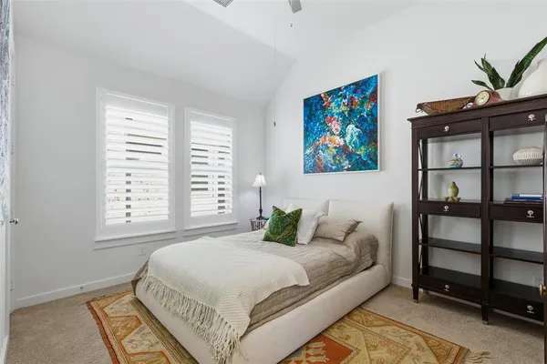 a bedroom with a bed a dresser and next to a window
