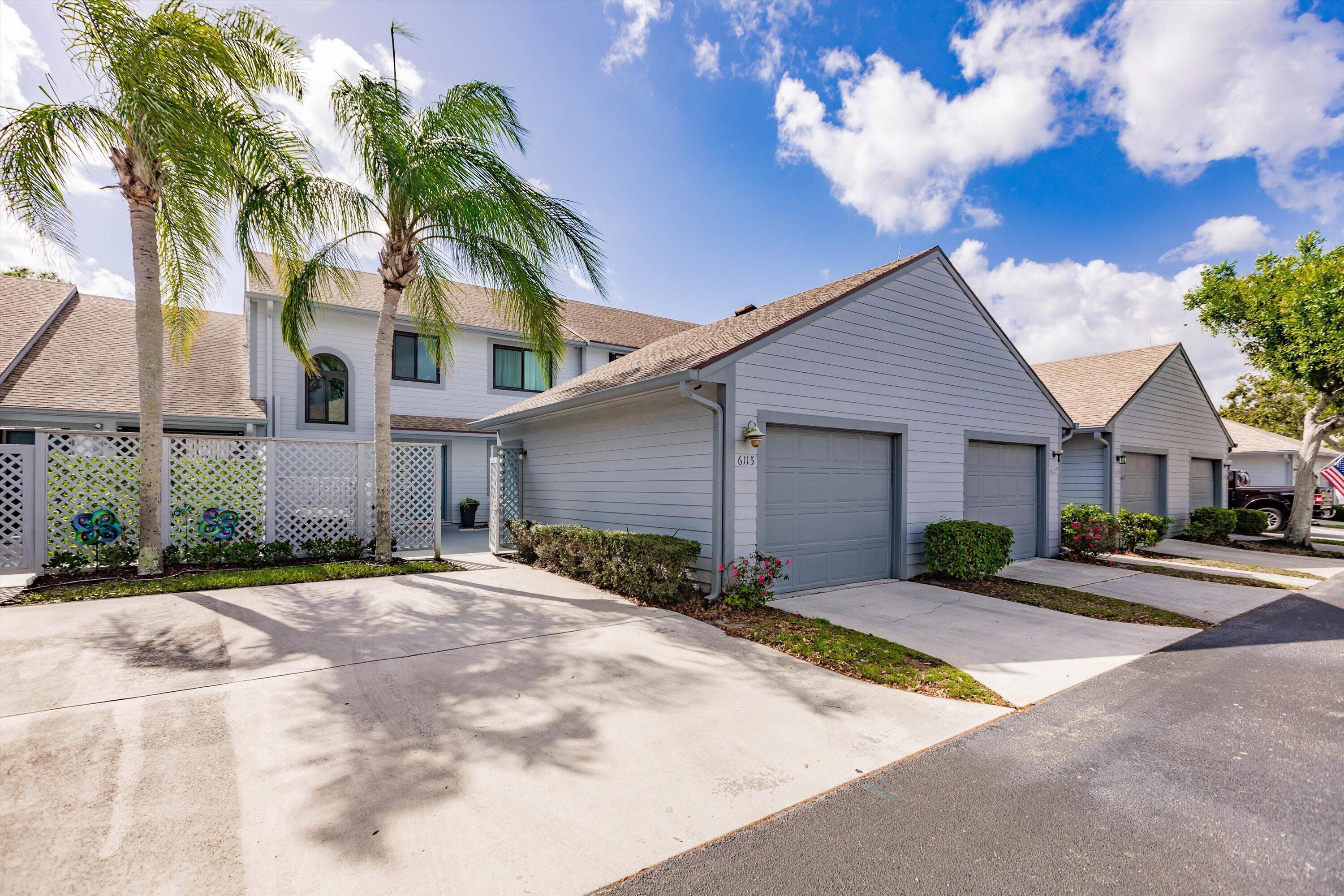 6115 Southeast Georgetown Place, Unit 1006 Hobe Sound, FL 33455 - Photo 2 of 68 a front view of a house with a yard and garage