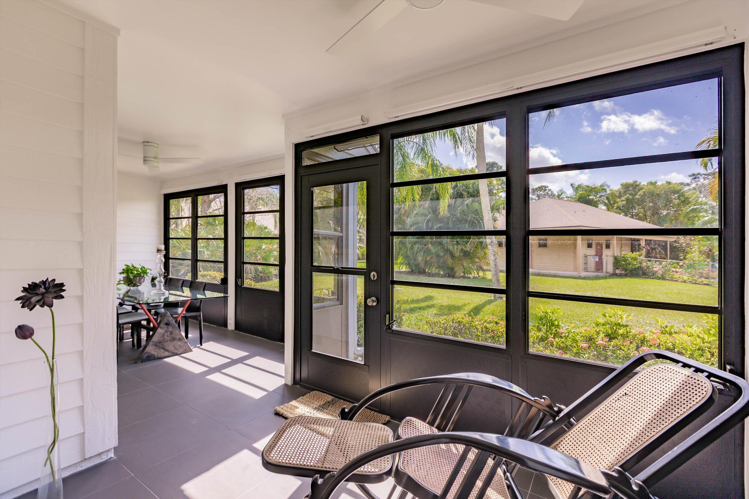 6115 Southeast Georgetown Place, Unit 1006 Hobe Sound, FL 33455 - Photo 38 of 68 a living room with furniture and floor to ceiling windows