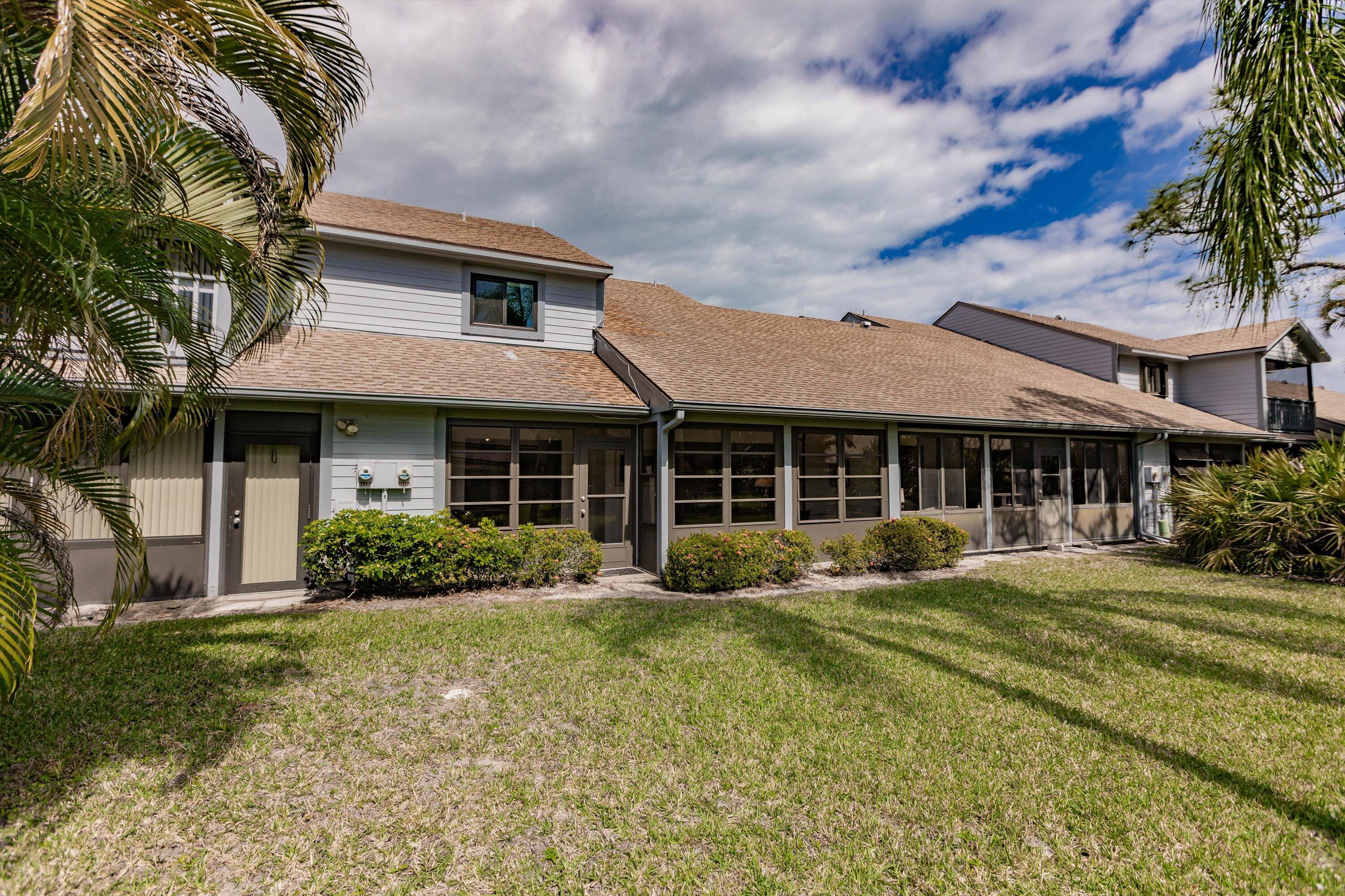 6115 Southeast Georgetown Place, Unit 1006 Hobe Sound, FL 33455 - Photo 47 of 68 a front view of a house with a yard