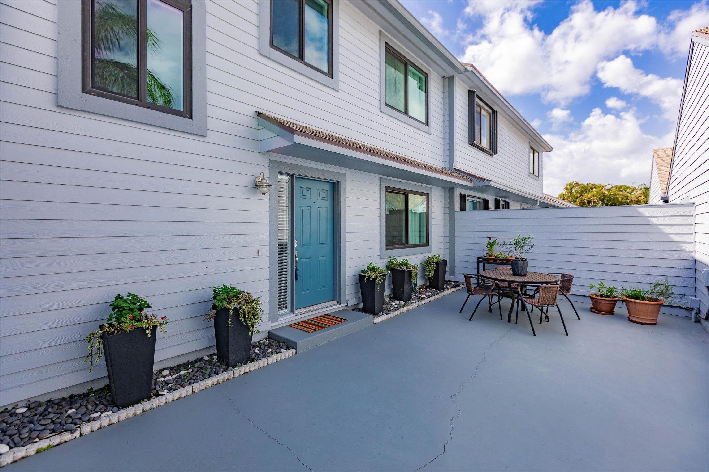 6115 Southeast Georgetown Place, Unit 1006 Hobe Sound, FL 33455 - Photo 51 of 68 a view of a patio with table and chairs and potted plants