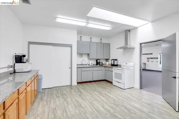 a large kitchen with stainless steel appliances a large counter top a stove and a wooden floors